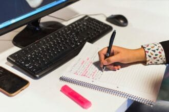 crop-hand-writing-notebook-near-computer_23-2147863504