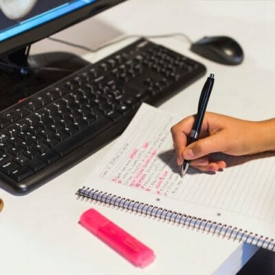 crop-hand-writing-notebook-near-computer_23-2147863504